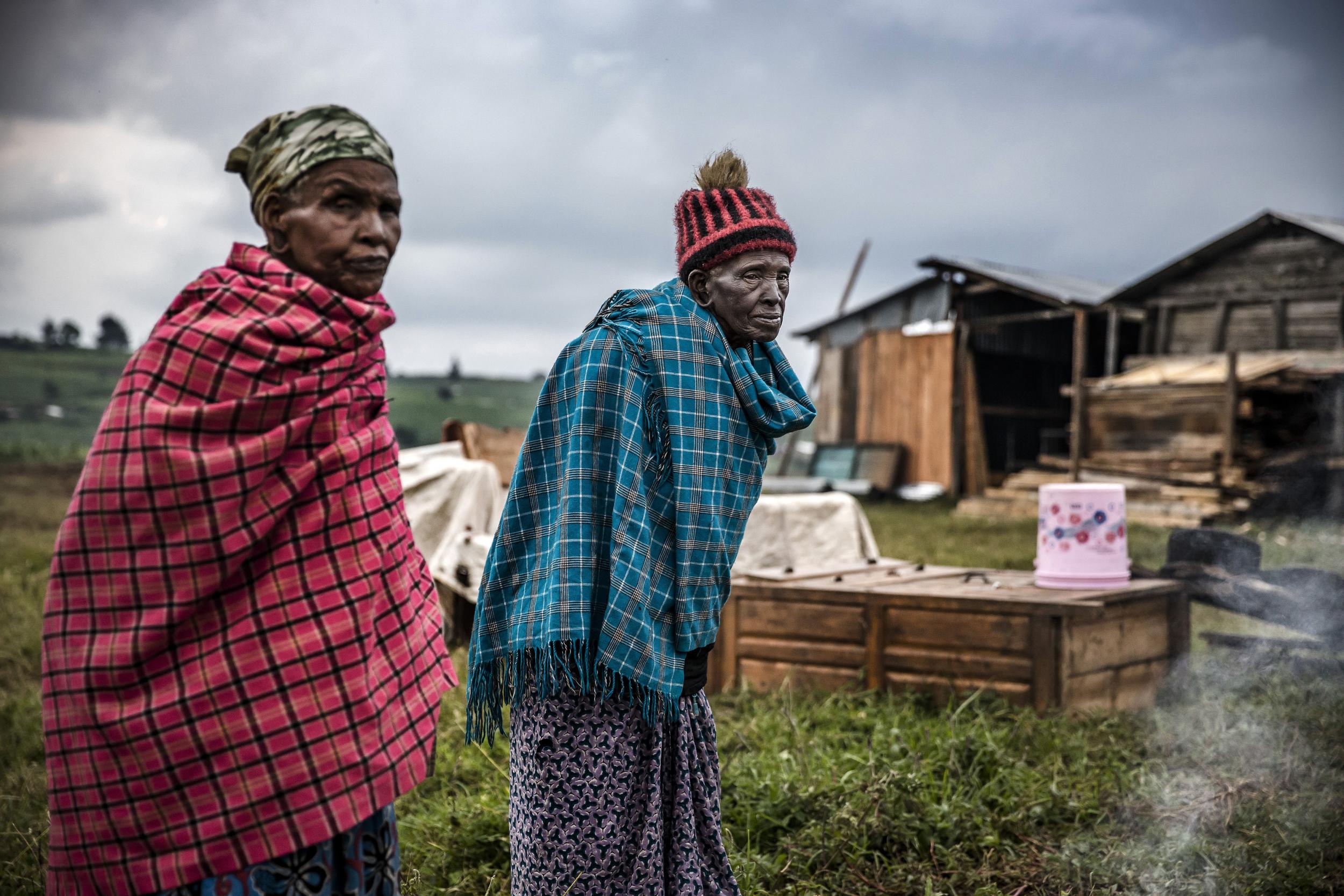 Agnes Tapkili (left) and Raeli Nalotwesha try to warm themselves near a small fire