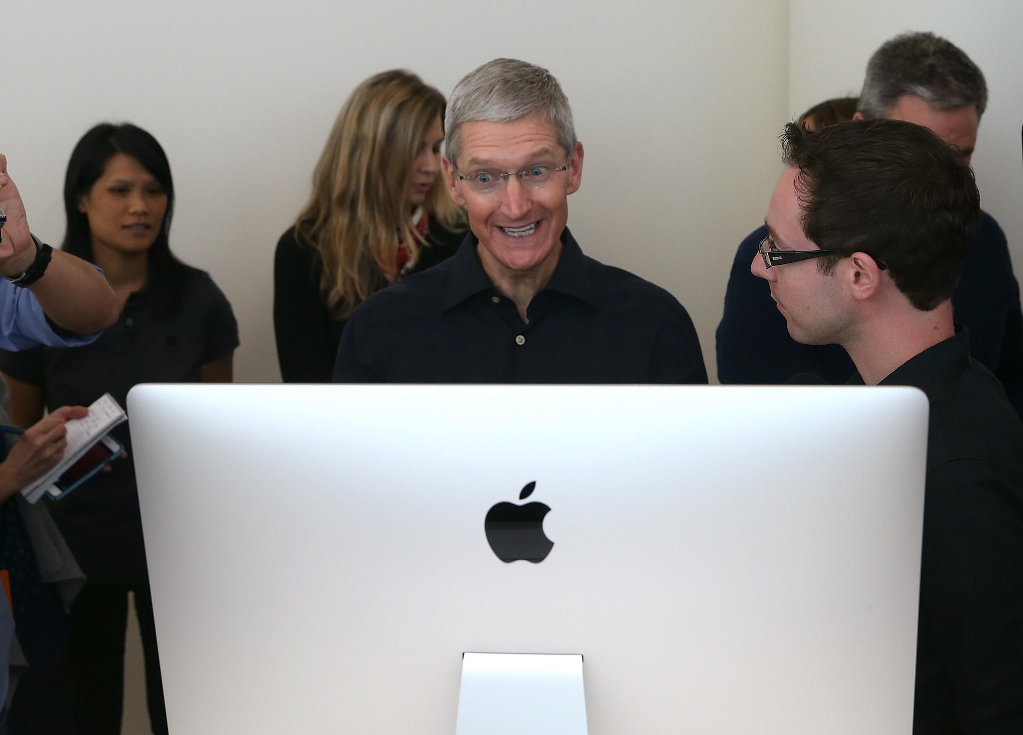 Apple CEO Tim Cook looks at the new 27 inch iMac with 5K retina display during an Apple special event on October 16, 2014 in Cupertino, California