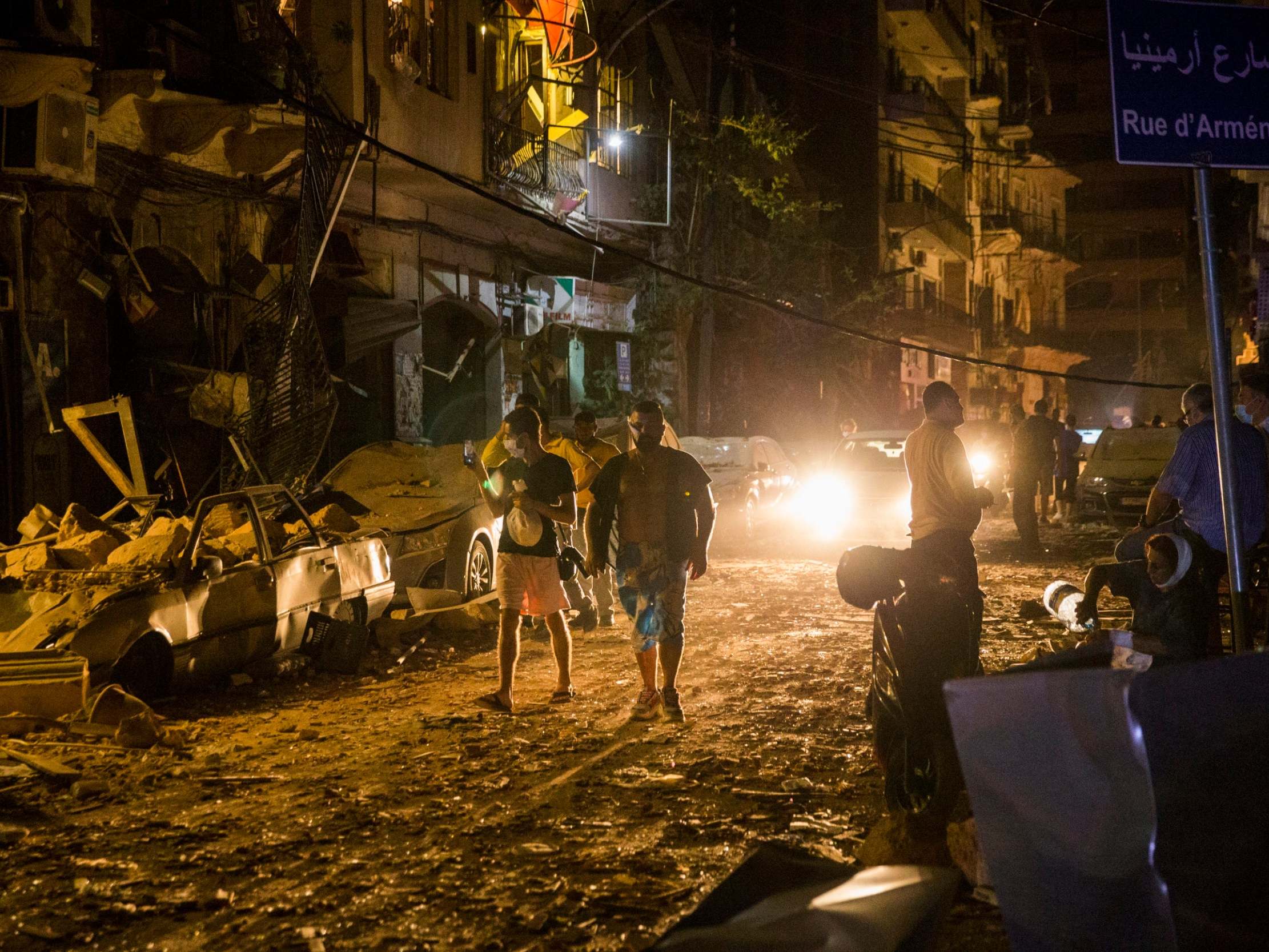 People walk on a street covered in debris