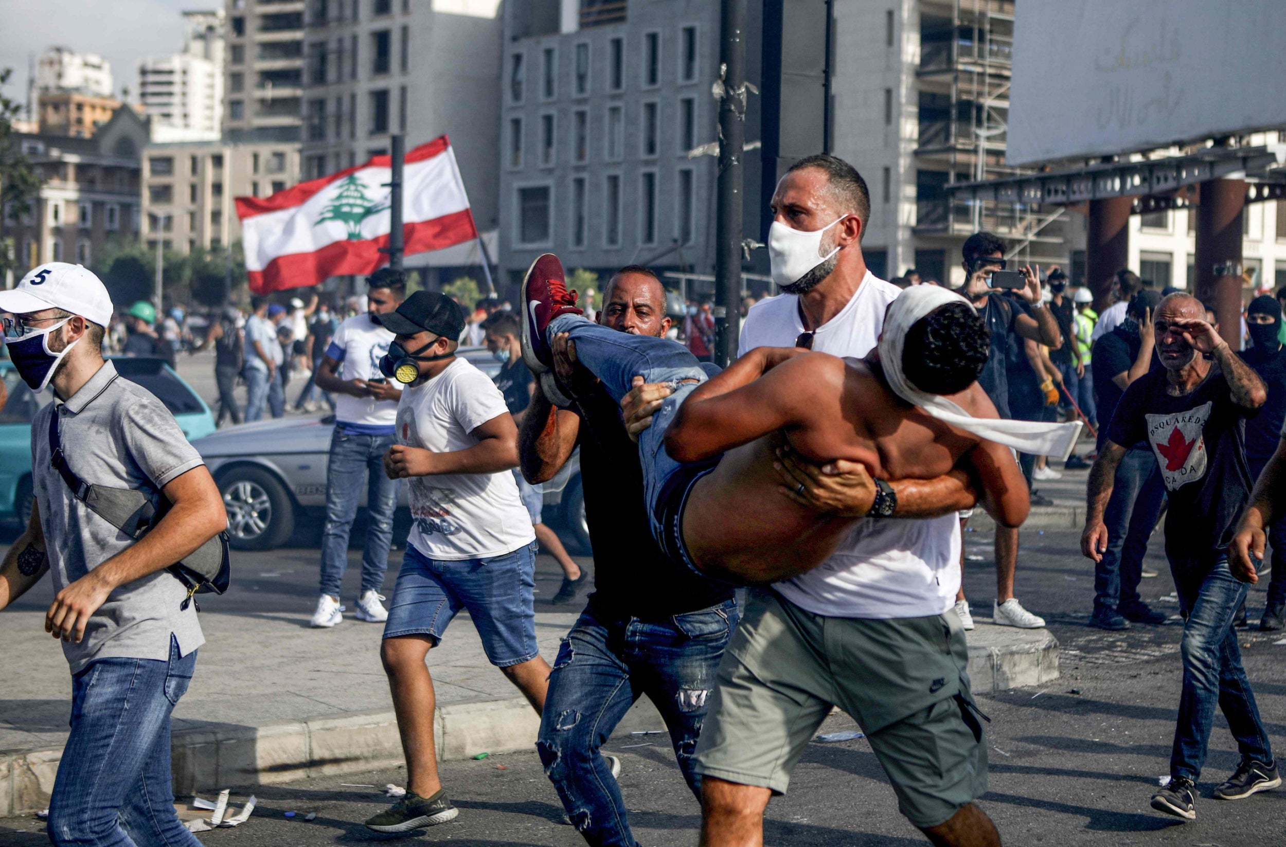 A Lebanese protester carries a wounded demonstrator away from clashes in downtown Beirut
