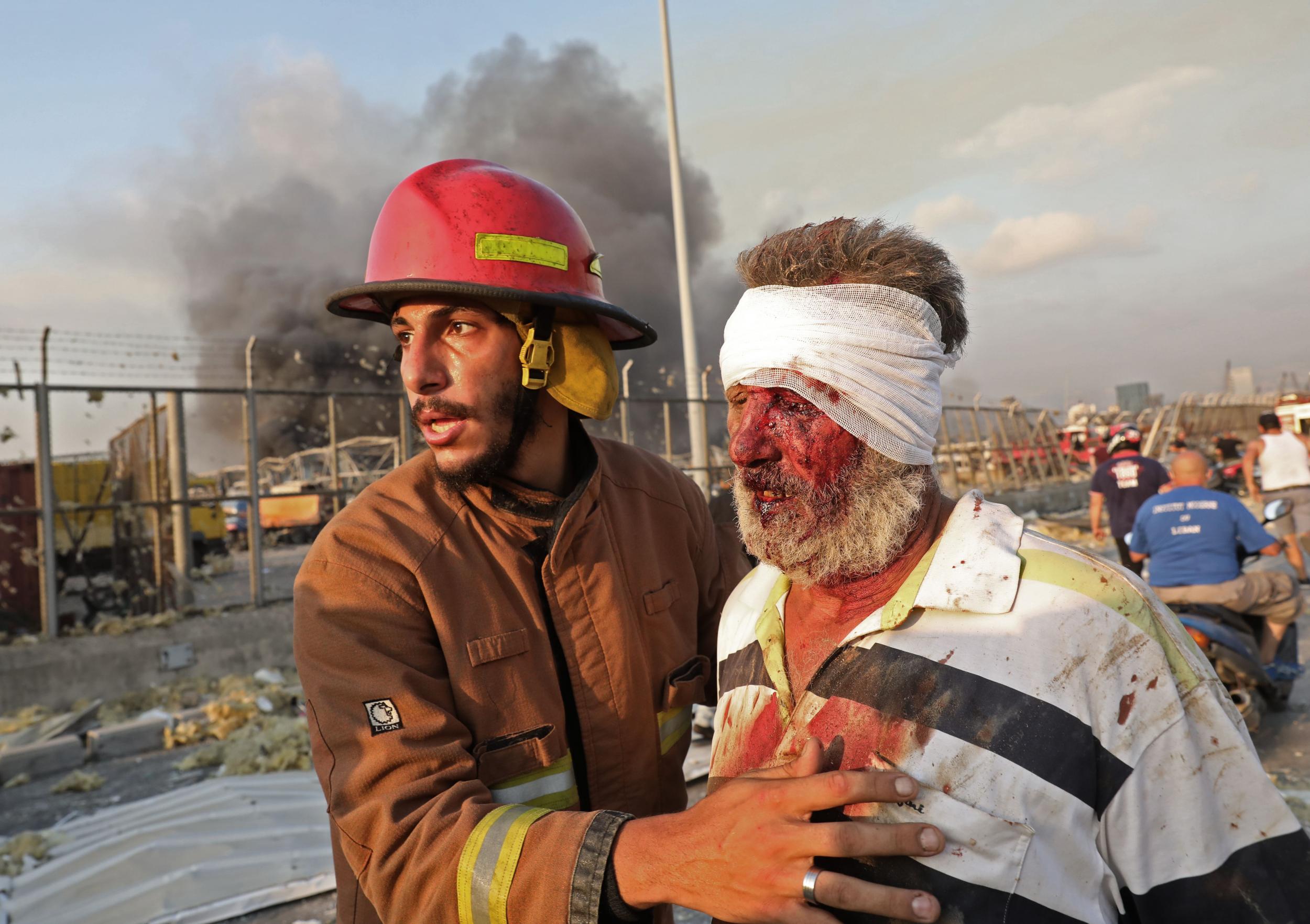 A wounded man is helped by a fireman near the scene of an explosion in Beirut on August 4, 2020