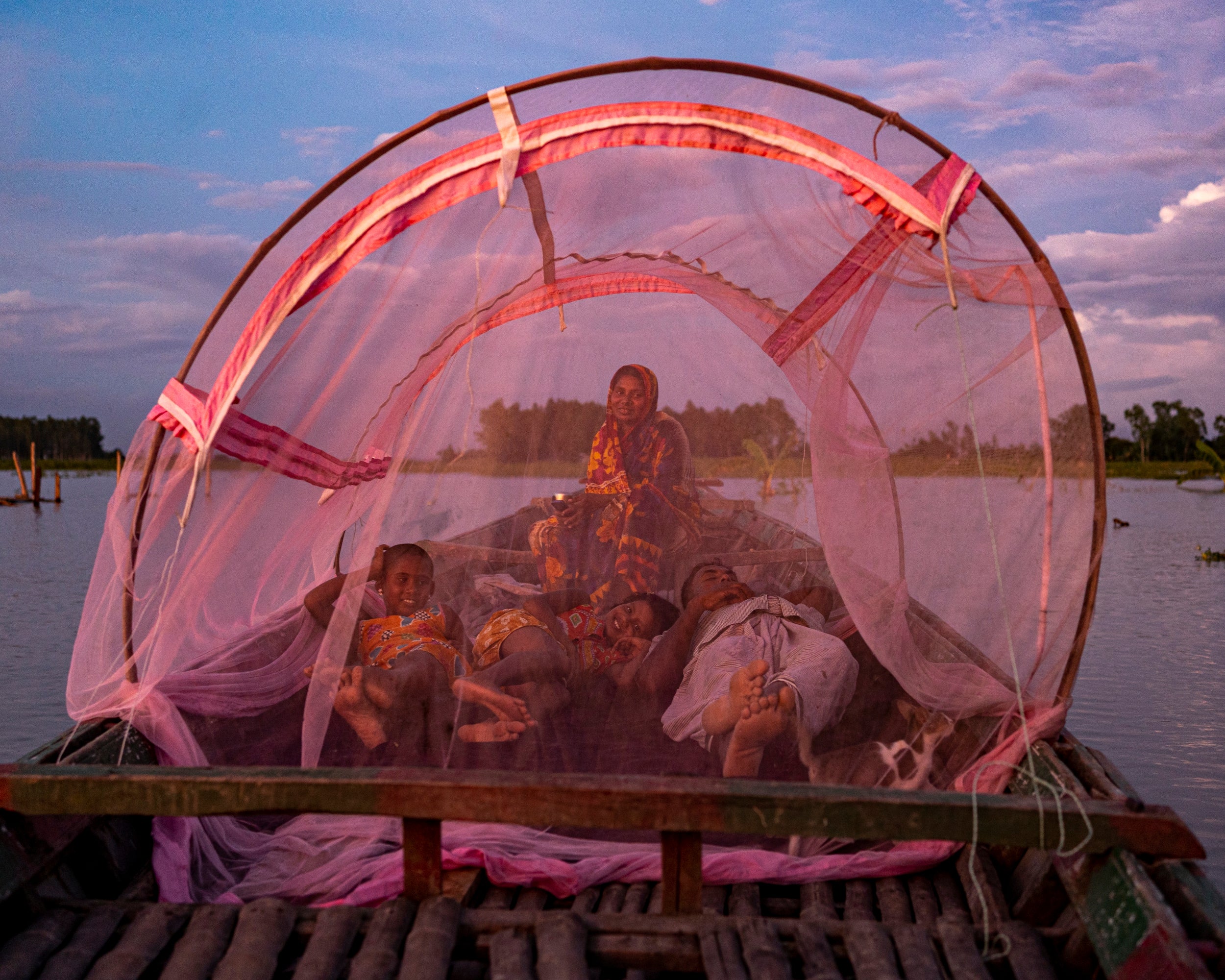 Shahidul Islam and Rowshan Ara, with their two daughters, Sayma and Sumaiya, under a mosquito net on their boat