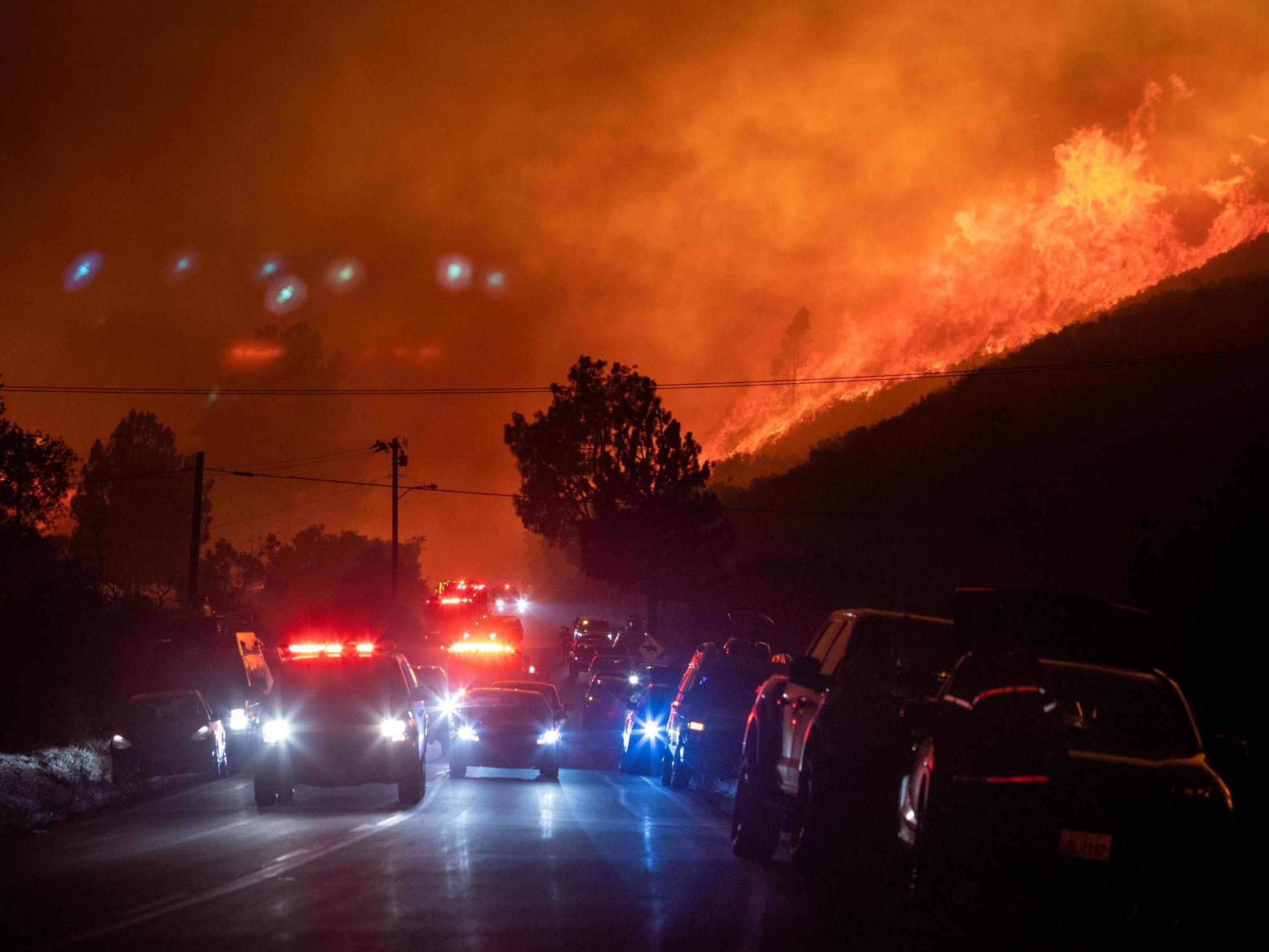 Firefighters and media flee from the flames of the Lake Fire in Lake Hughes, California, 12 August