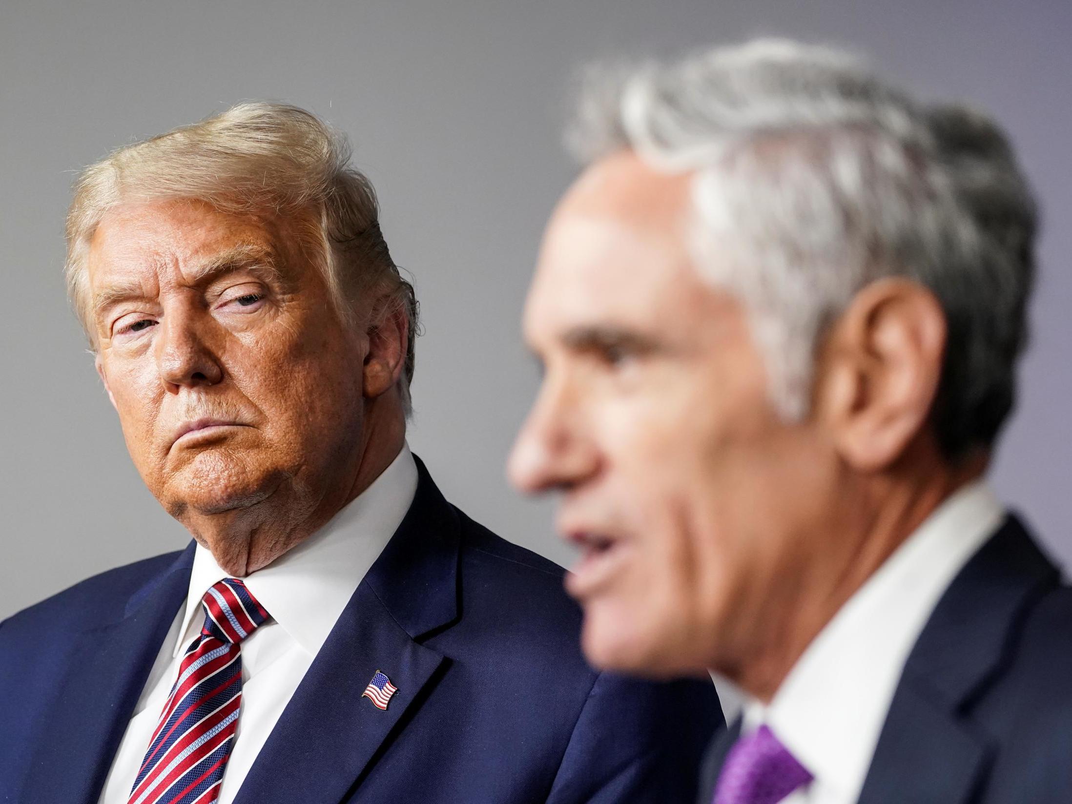 Donald Trump listens as Dr Scott Atlas, the newest member of the administration's coronavirus task force, speaks during a briefing on the coronavirus disease