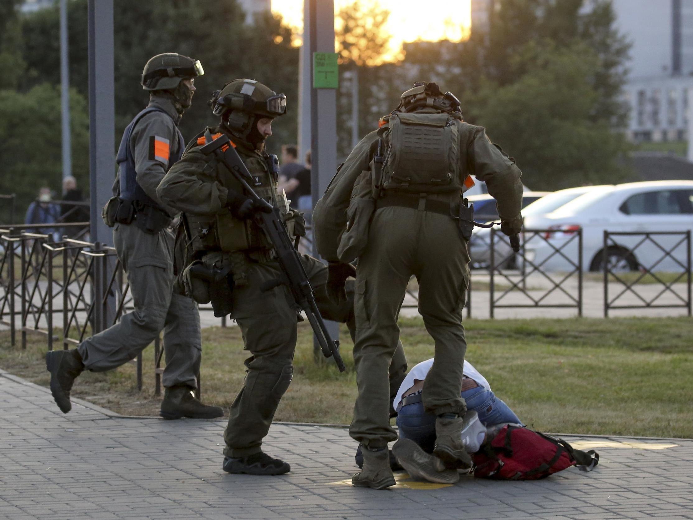 Police officers kick a demonstrator during a protest of the disputed presidential election in Minsk, Belarus