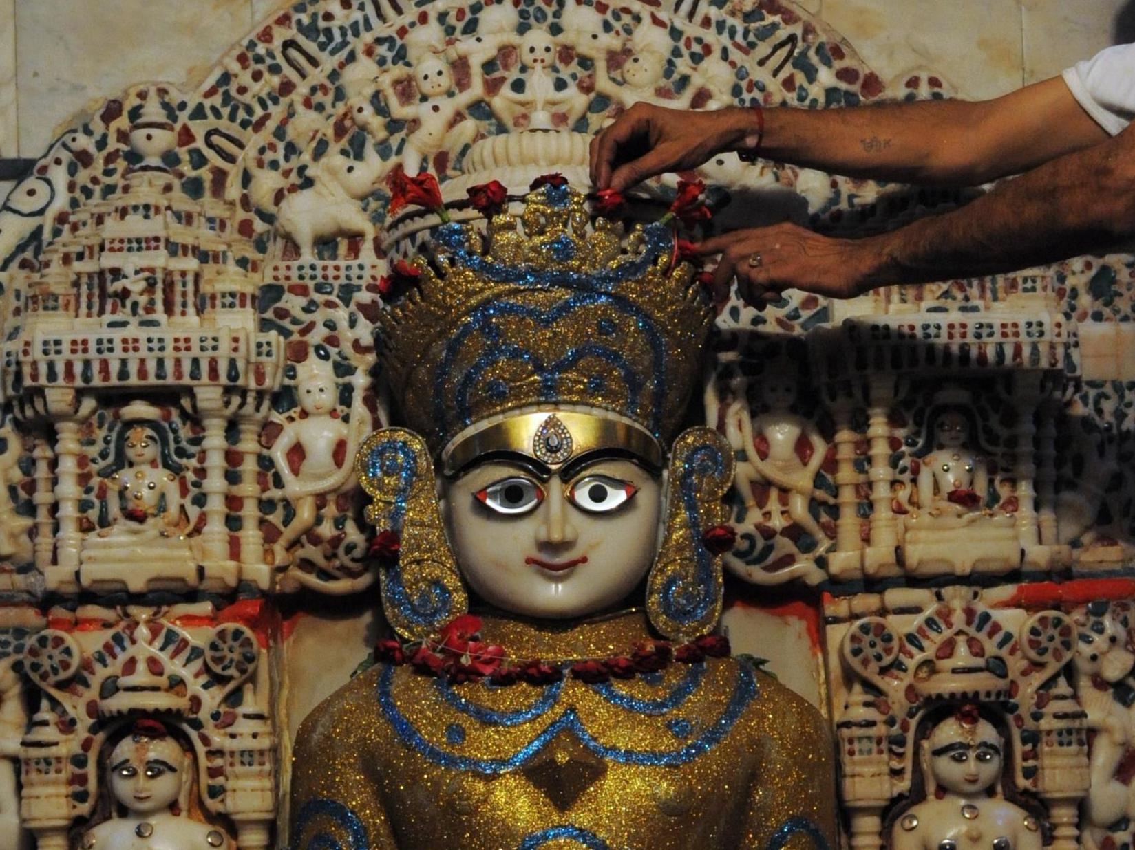 An Indian Jain priest decorates an ancient idol of Lord Mahavir Swami don the eve of Mahavir Janma Vanchan Divas, 15 September 2012. Mahavir Janma Vanchan Divas is the 5th day of Paryushan.