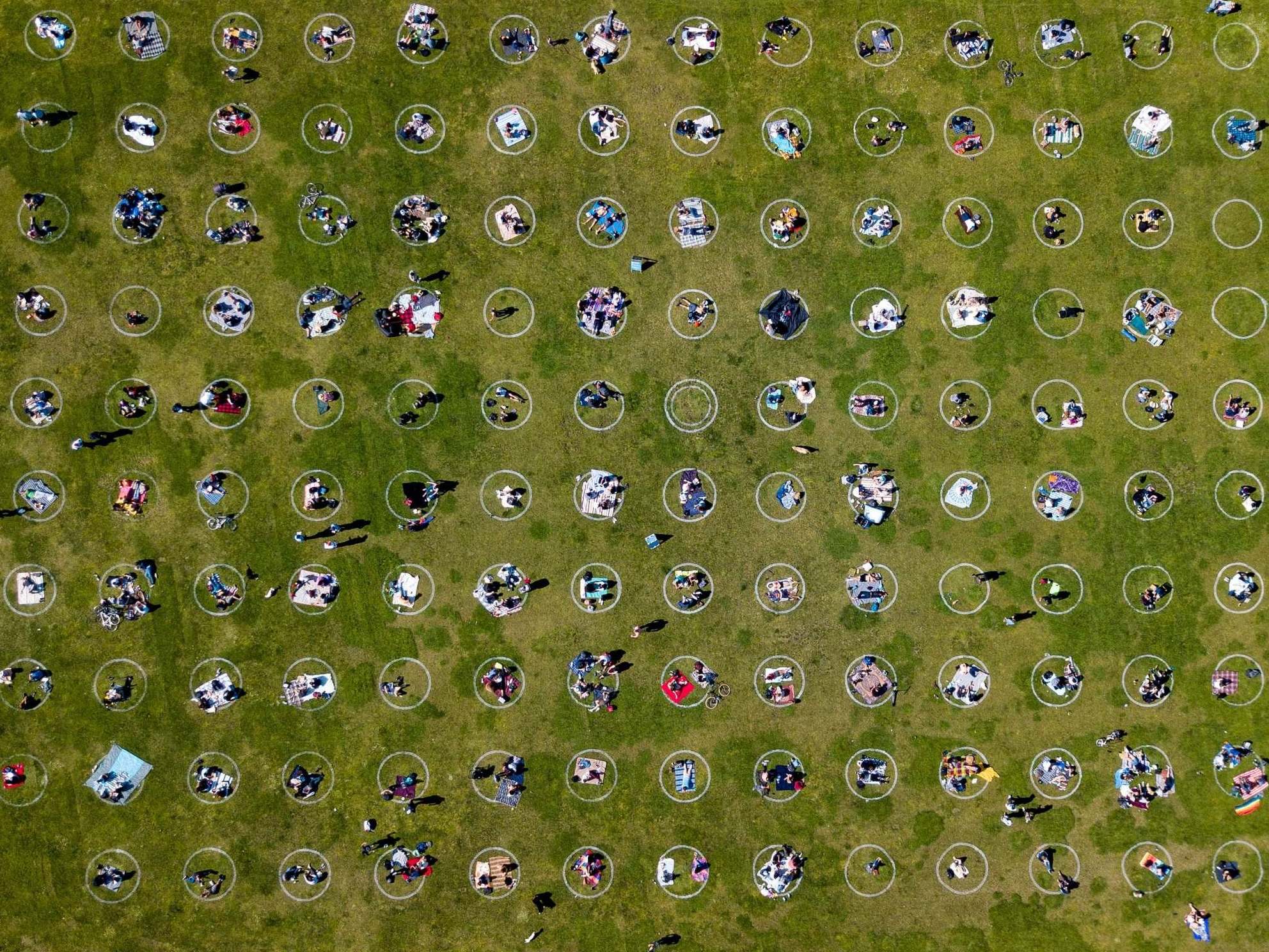 People gather inside painted circles on the grass encouraging social distancing at Dolores Park in San Francisco