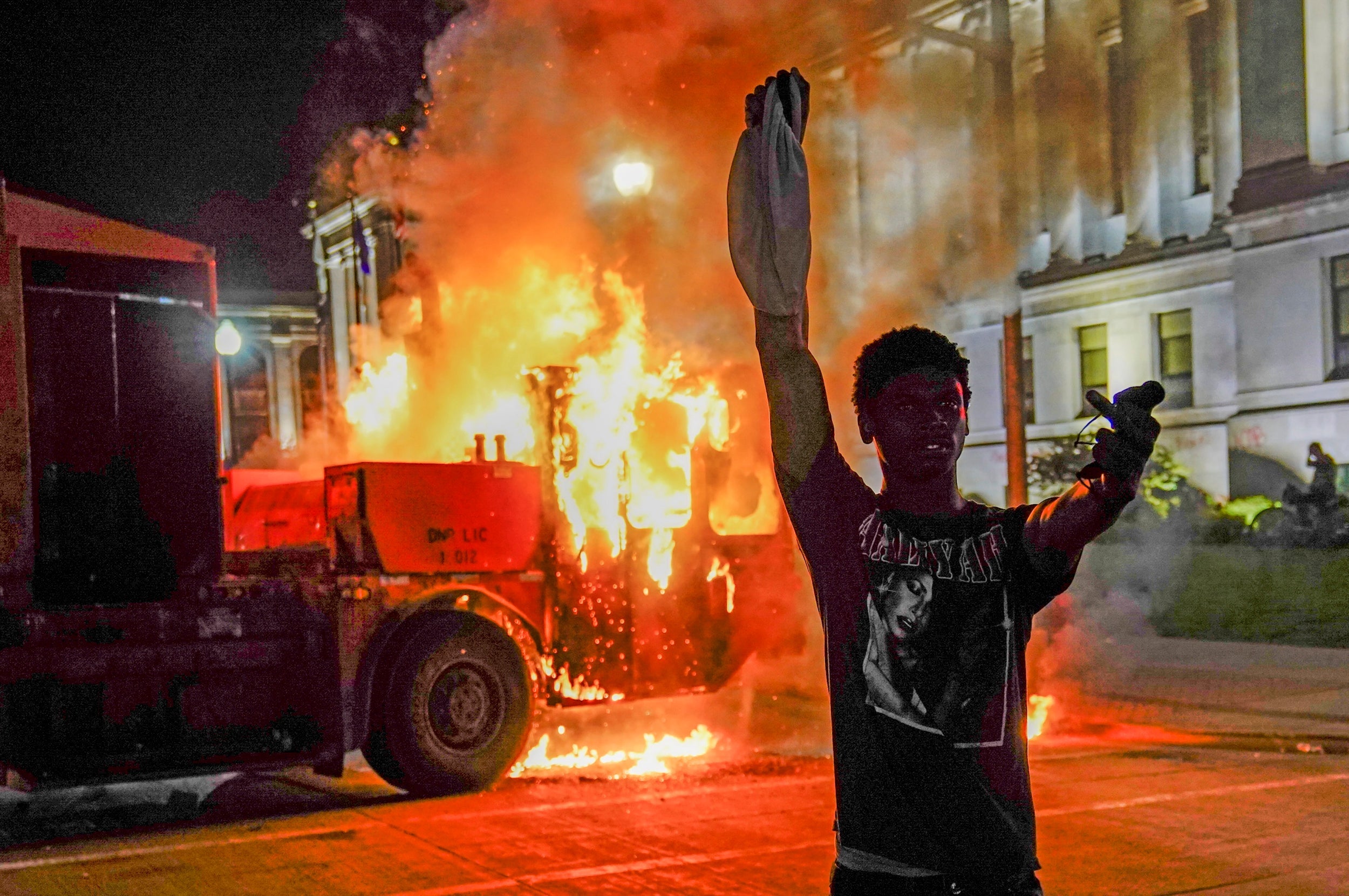 A protester in front of a burning truck in Kenosha, Wisconsin during unrest following the police shooting of Jacob Blake