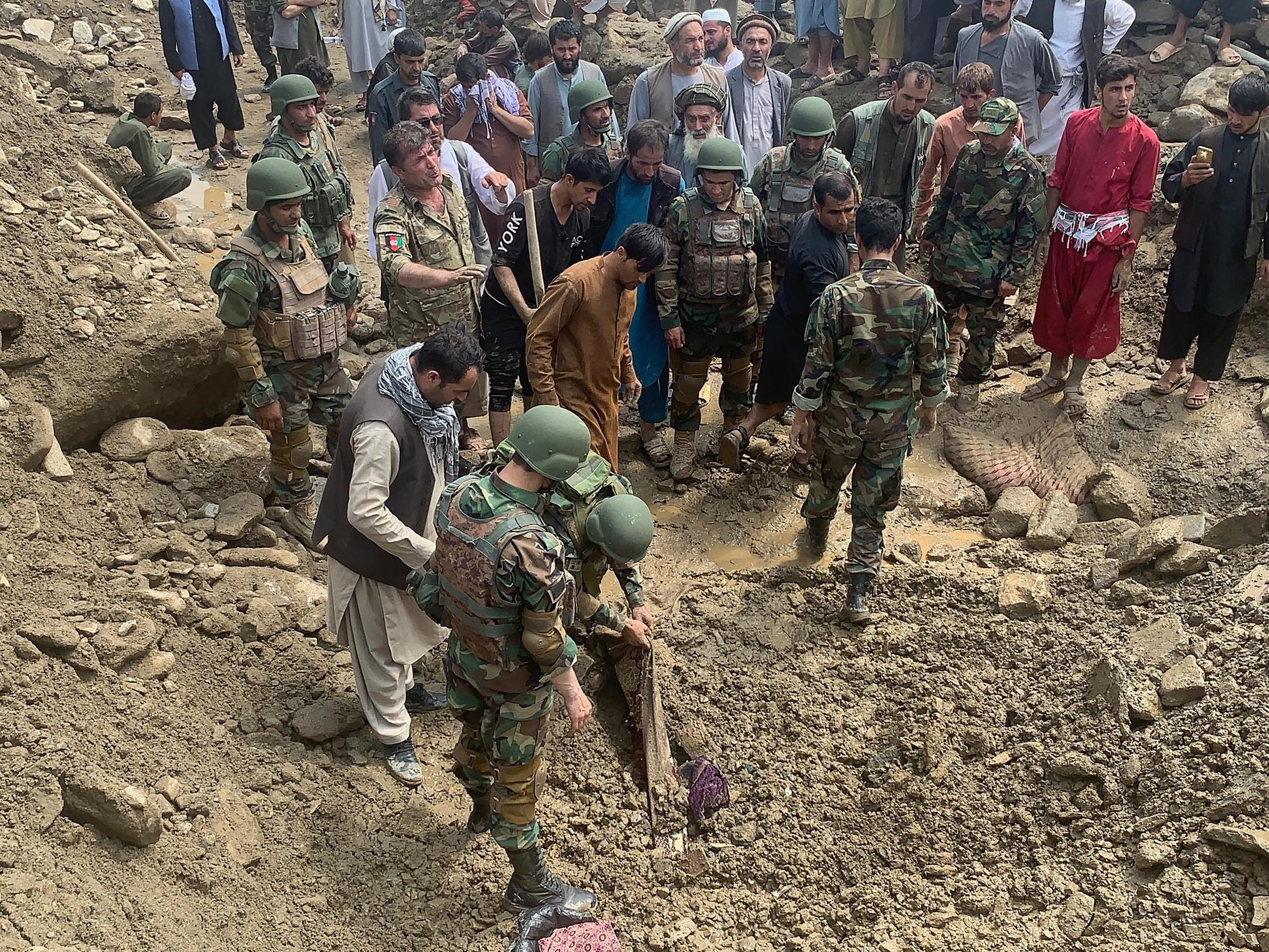 Soldiers and locals search for victims in a mudslide following heavy flooding in the Parwan province, north of Kabul, in Afghanistan