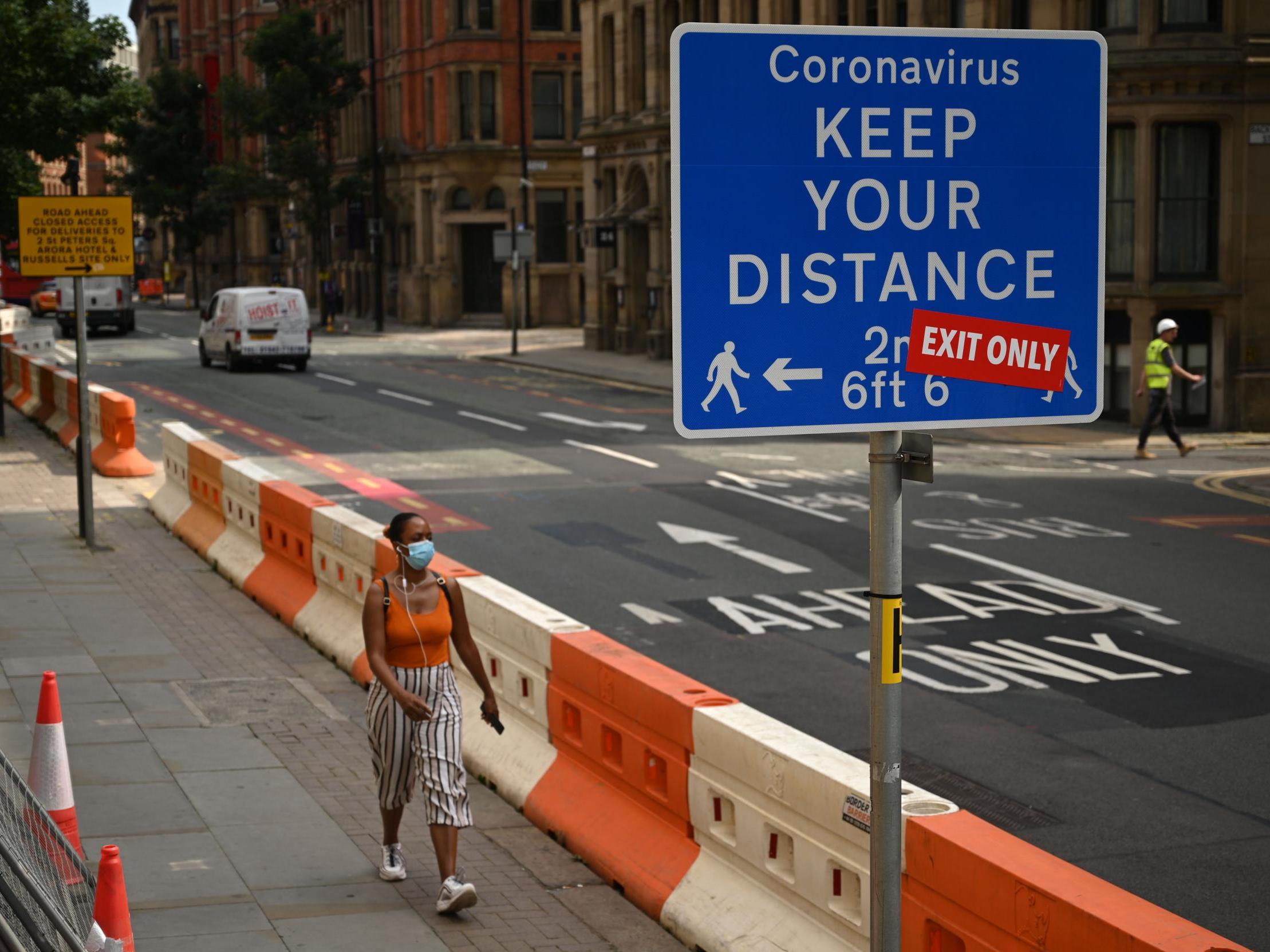 A lonely stroller heads out in Manchester, where greater lockdown restrictions were brought into effect at the end of July