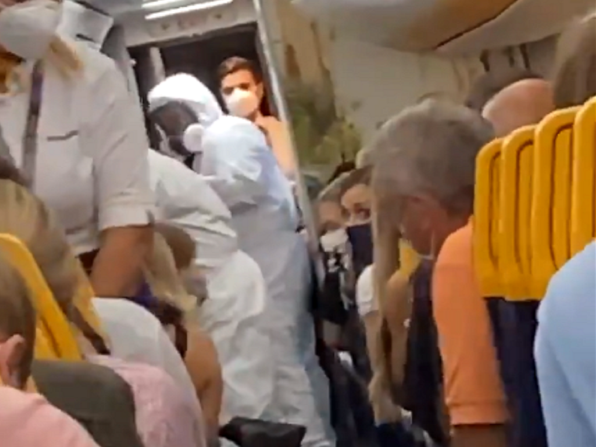 Still image taken from video of officials in hazmat suits removing two passengers from a Ryanair flight at Stansted Airport after one of them tested positive for coronavirus.