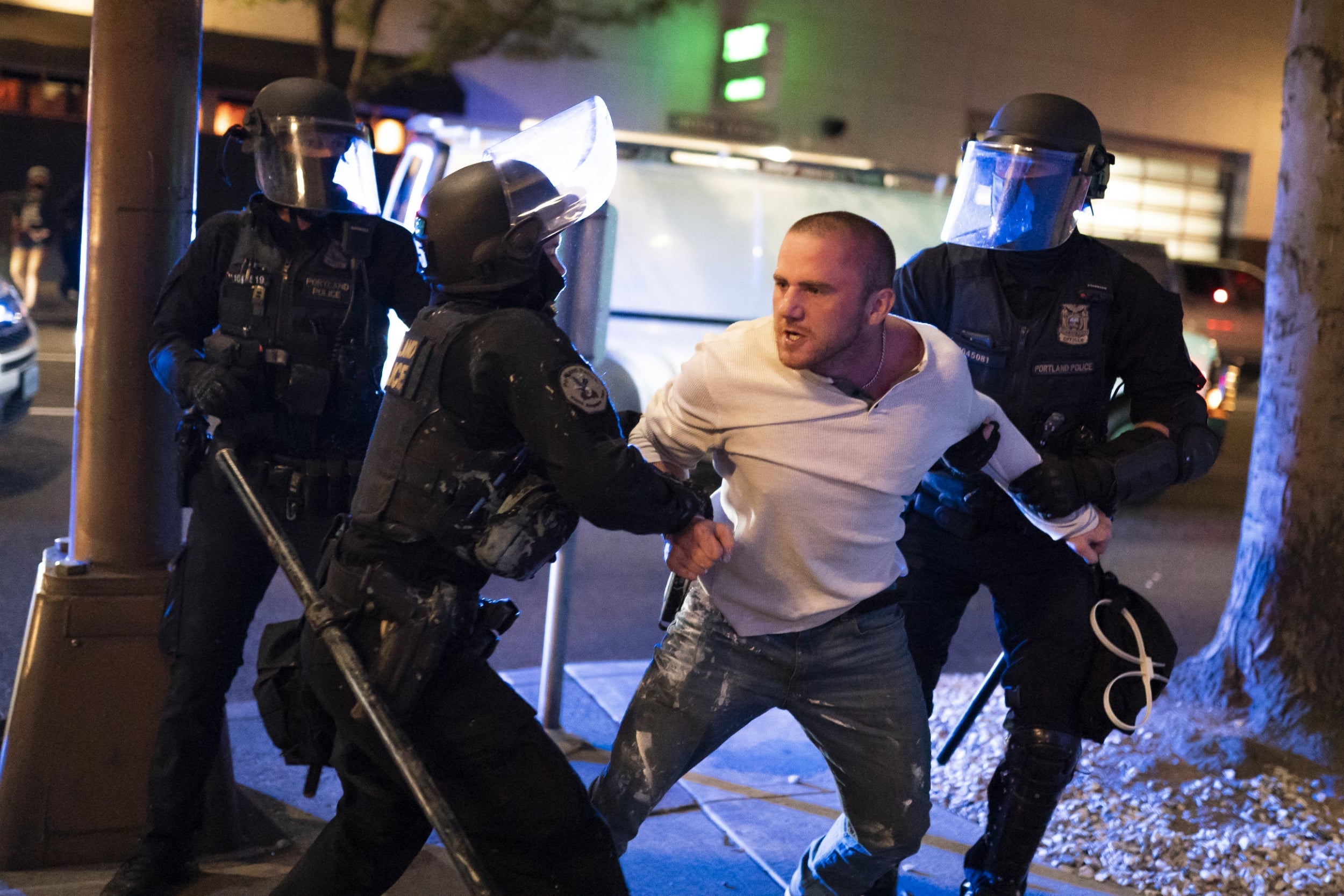 Portland police hold back a man who was with the victim of a fatal shooting as he reacts in minutes after the incident on August 29, 2020 in Portland, Oregon