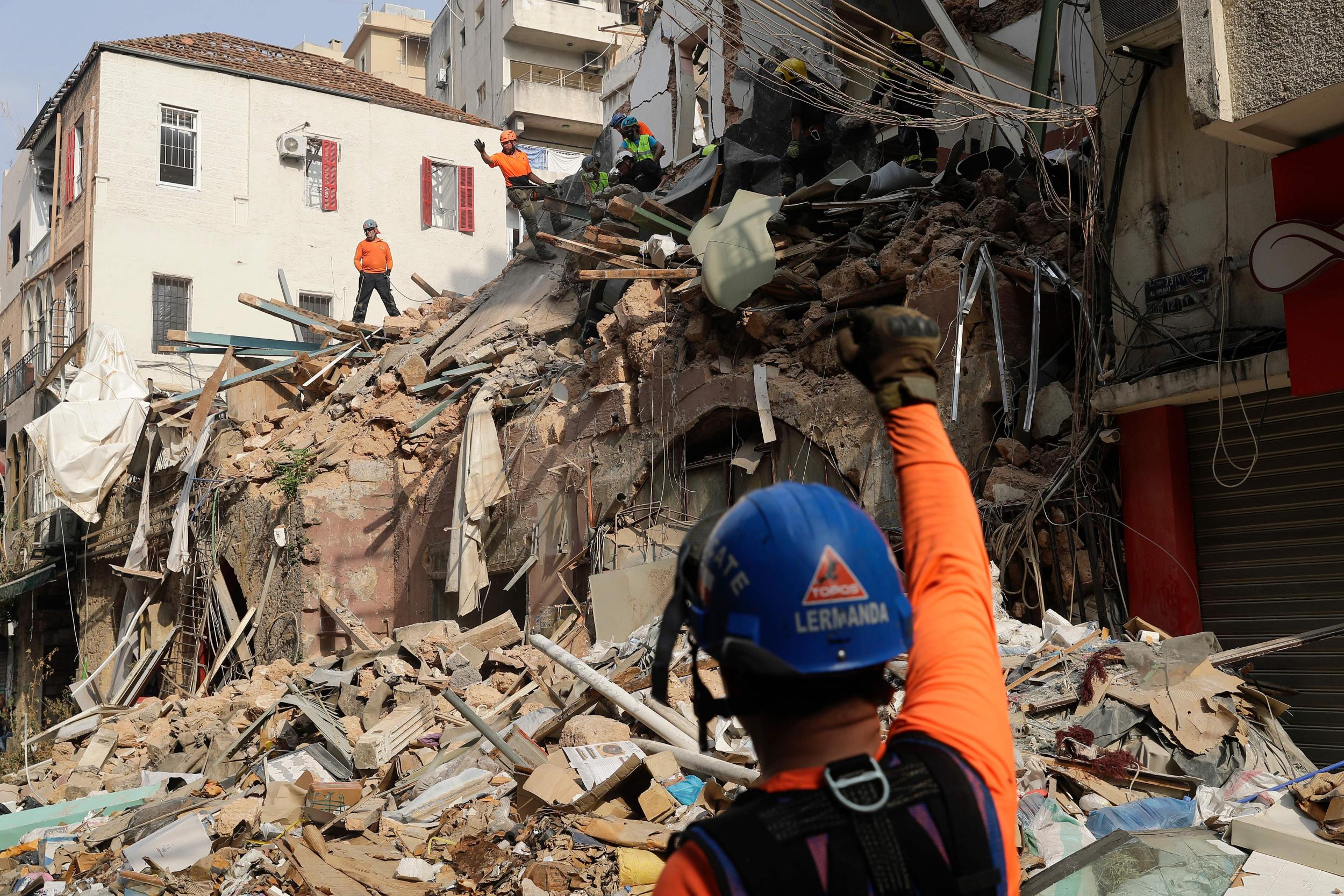 Rescue workers dig through the rubble of a badly damaged building in Lebanon's capital Beirut, in search of possible survivors from a mega-blast