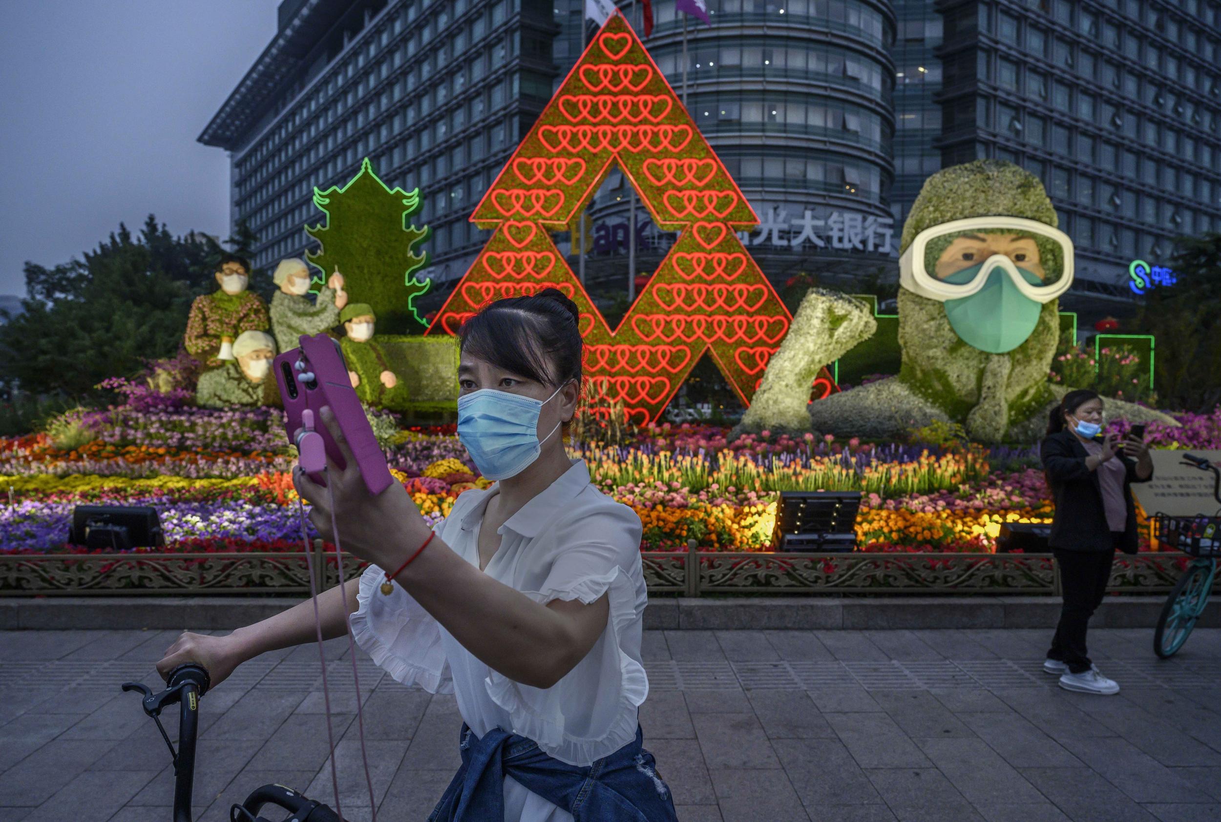 A Chinese woman takes a photo of herself in front of a flower display dedicated to frontline health care workers during the COVID-19 pandemic in Beijing, China. China will celebrate national day marking the founding of the People's Republic of China on October 1st