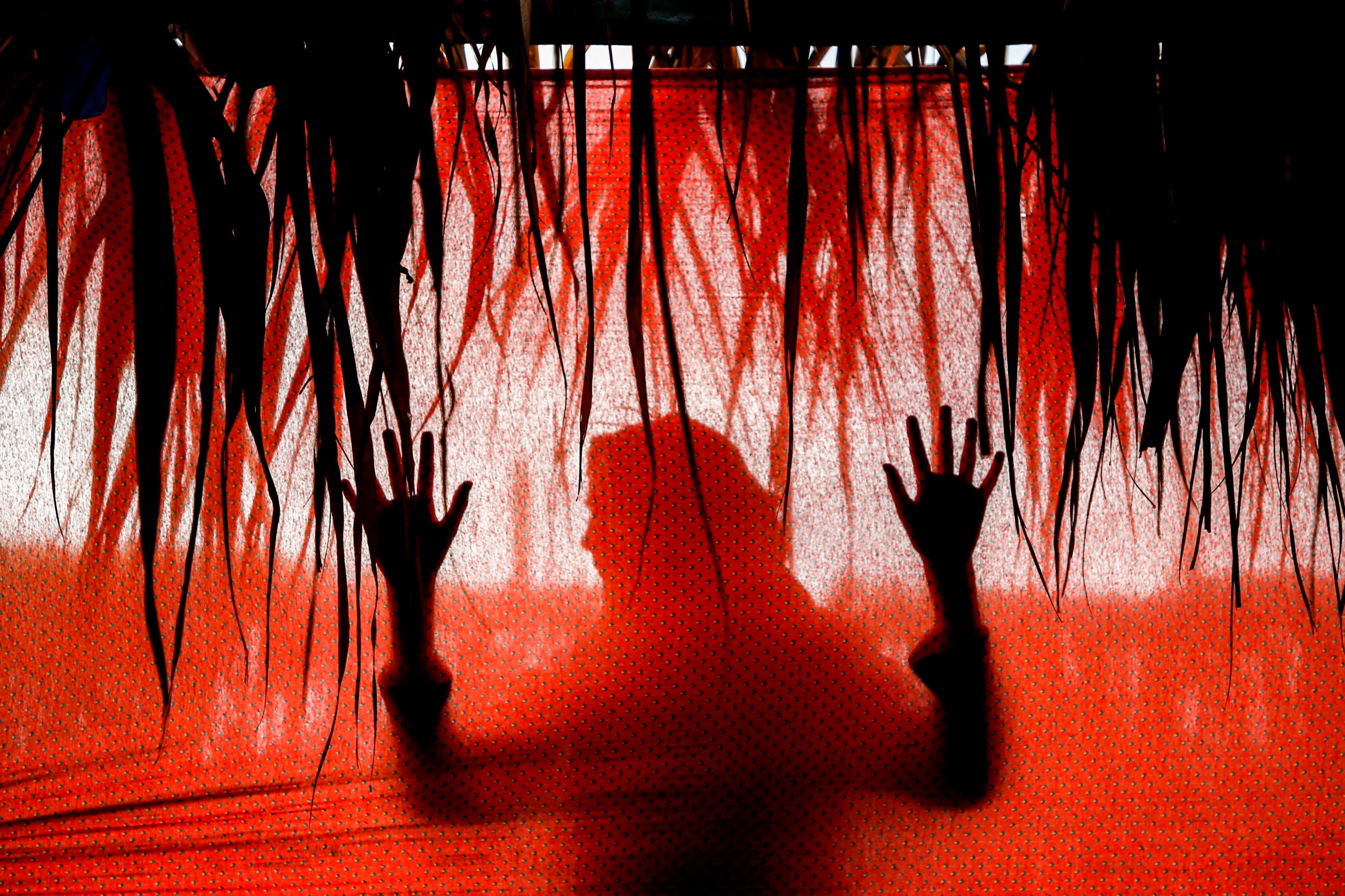 A girl's silhouette is seen from behind a fabric in a tent along a beach by Beit Lahia in the northern Gaza Strip