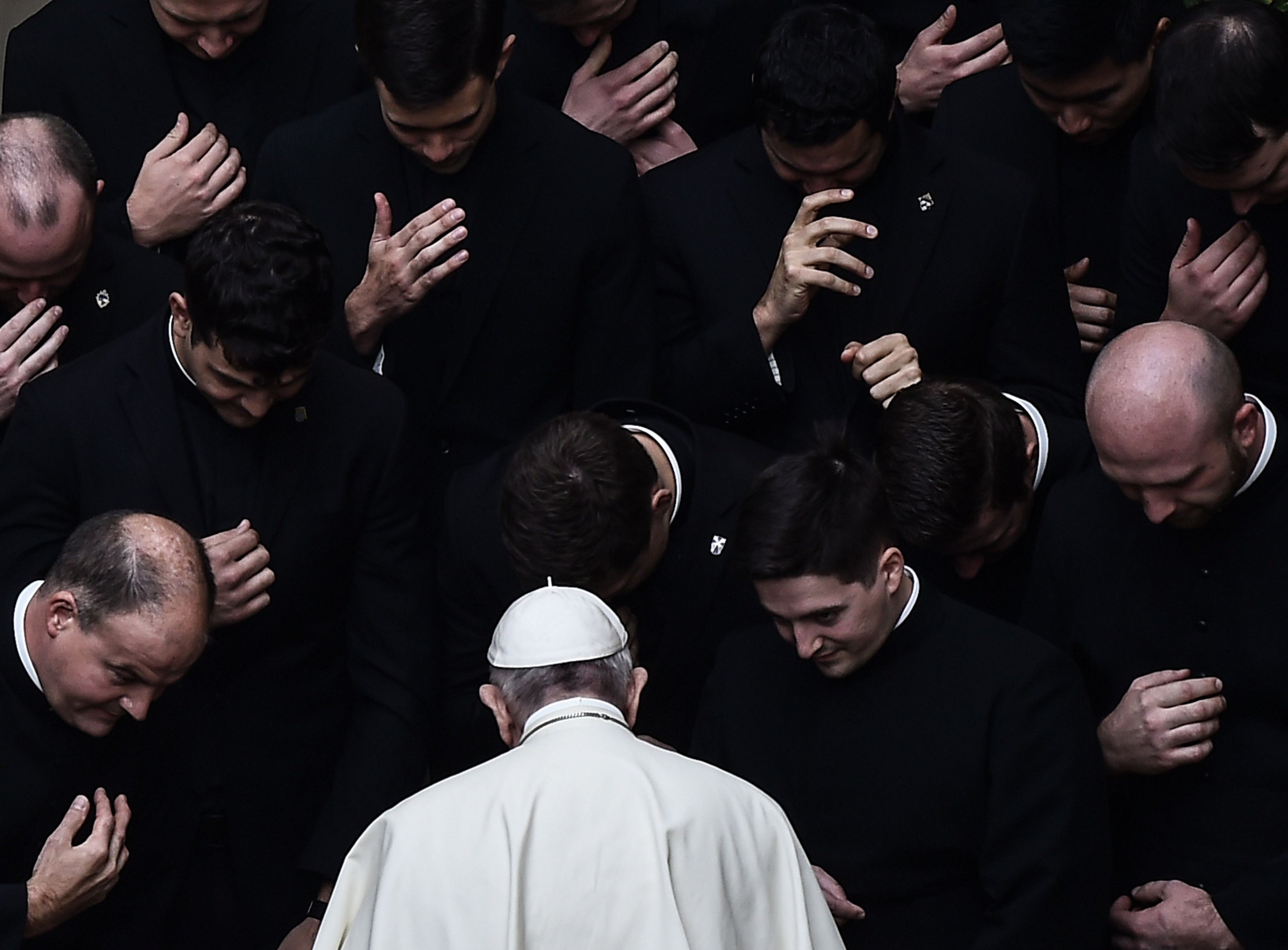 Pope Francis prays with priests at the end of a limited public audience at the San Damaso courtyard in The Vatican